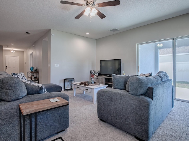 living room featuring light carpet, ceiling fan, and a textured ceiling