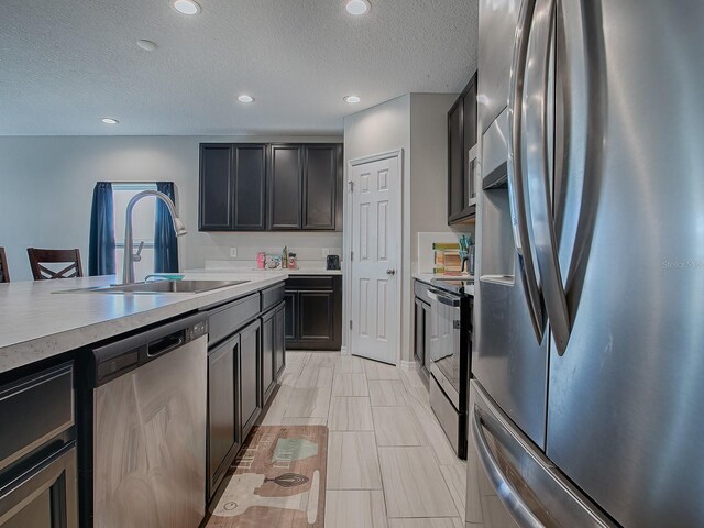 kitchen with appliances with stainless steel finishes, a textured ceiling, and sink