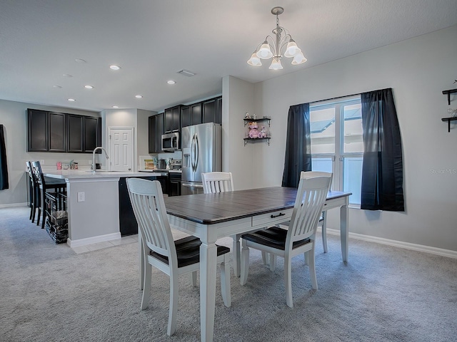 dining area with light colored carpet, a notable chandelier, and sink