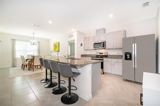 kitchen featuring appliances with stainless steel finishes, sink, an island with sink, a kitchen breakfast bar, and dark stone counters