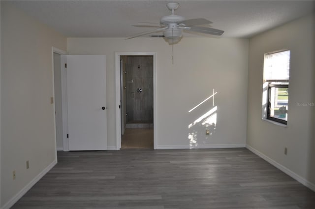 unfurnished room with ceiling fan, dark wood-type flooring, and a textured ceiling