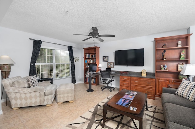 living room featuring ceiling fan, light tile patterned floors, built in desk, and a textured ceiling