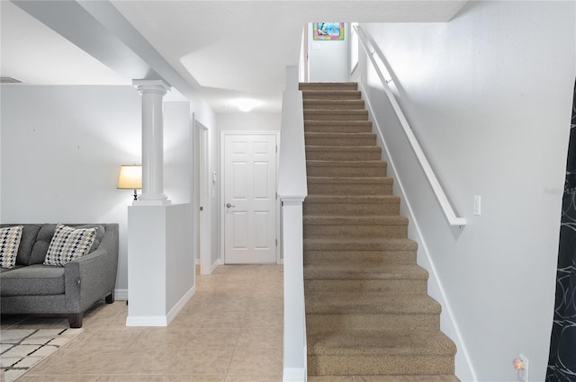 staircase with decorative columns and tile patterned floors