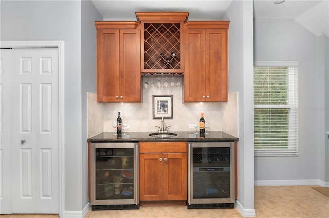 bar with sink, backsplash, beverage cooler, and dark stone countertops