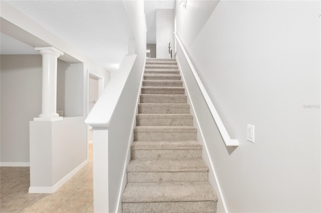 stairway featuring tile patterned flooring and ornate columns