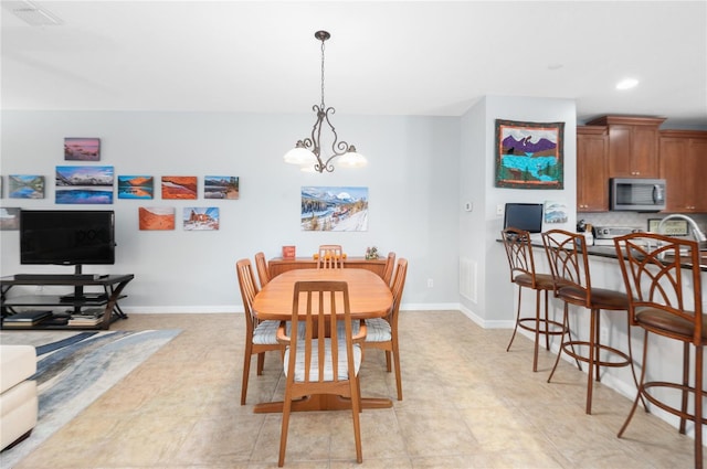 dining area with sink, light tile patterned floors, and an inviting chandelier