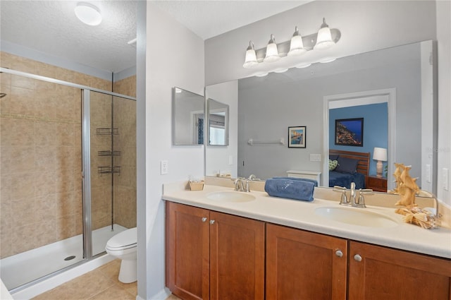 bathroom with toilet, a textured ceiling, vanity, a shower with door, and tile patterned flooring