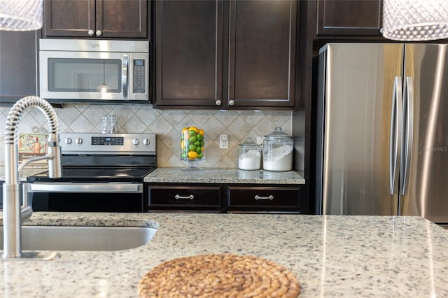 kitchen with light stone countertops, appliances with stainless steel finishes, sink, backsplash, and dark brown cabinets