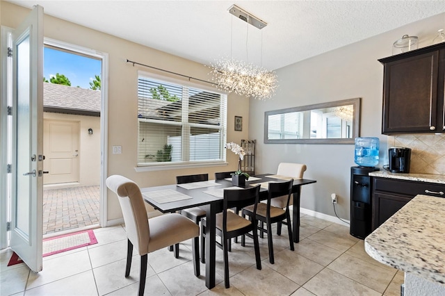 dining area with light tile patterned flooring, a notable chandelier, and a textured ceiling