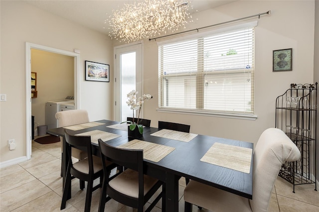 dining area featuring independent washer and dryer, light tile patterned floors, plenty of natural light, and a chandelier