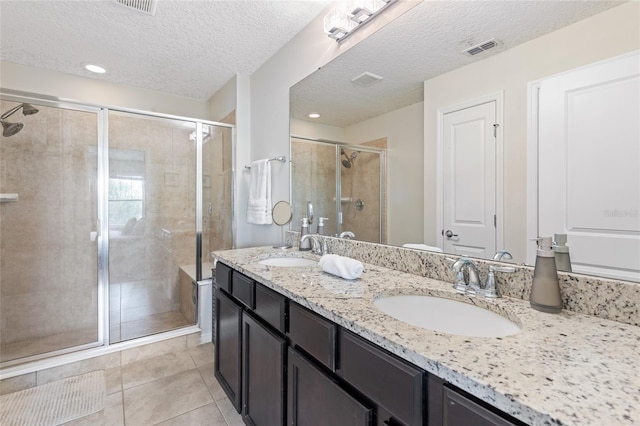 full bathroom with a shower stall, double vanity, tile patterned flooring, and a textured ceiling