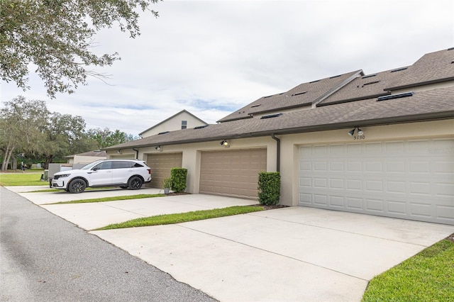 view of side of home with driveway, roof with shingles, and stucco siding