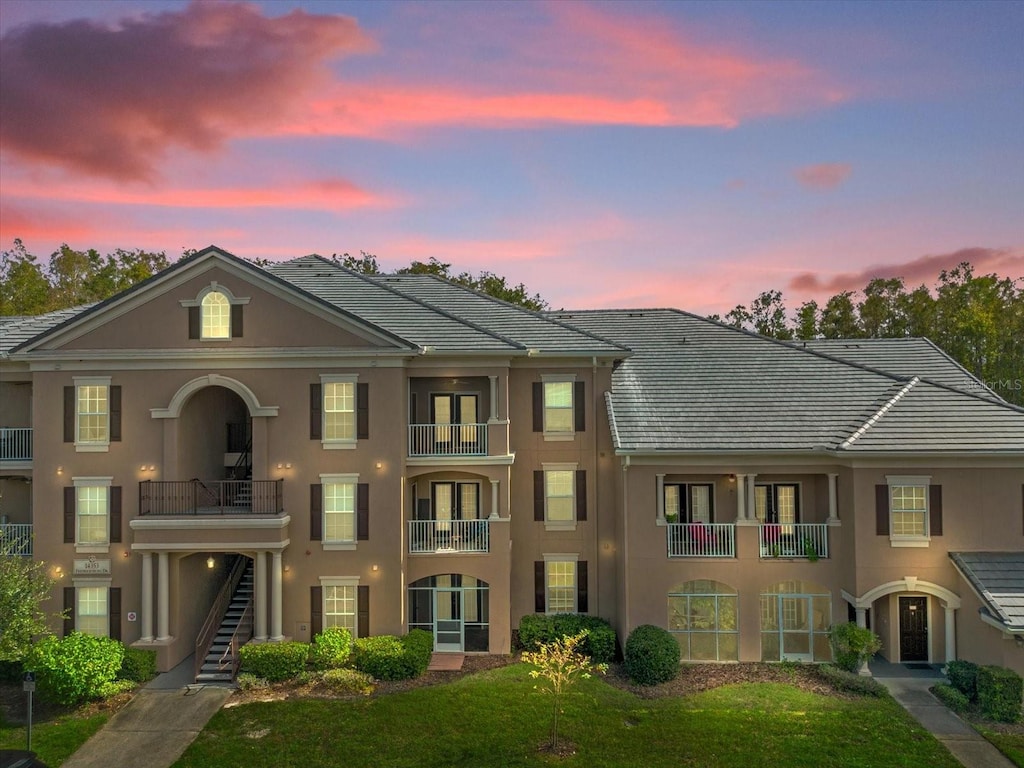 view of front of property featuring a balcony and a yard