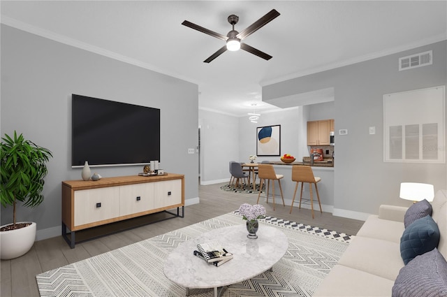 living room with light hardwood / wood-style floors, ornamental molding, and ceiling fan