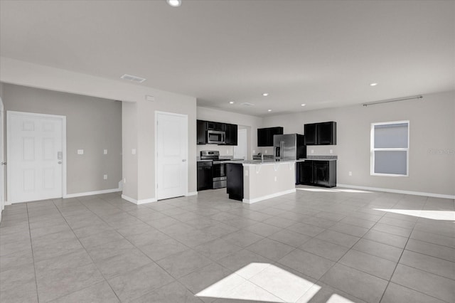 kitchen featuring appliances with stainless steel finishes, a kitchen island with sink, and light tile patterned flooring