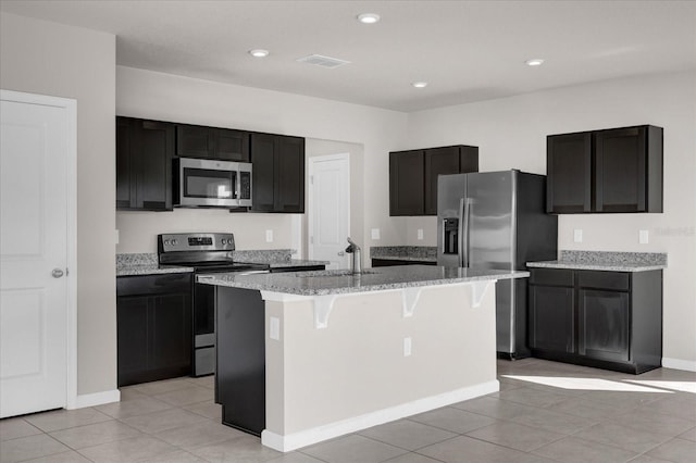 kitchen featuring light stone counters, stainless steel appliances, a kitchen island with sink, sink, and light tile patterned floors