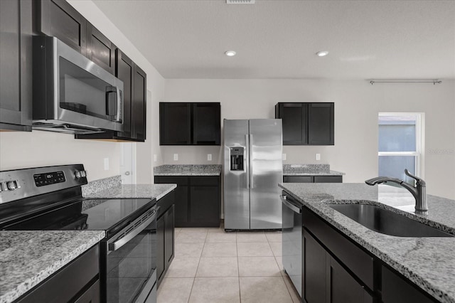 kitchen featuring light stone counters, sink, light tile patterned floors, and stainless steel appliances