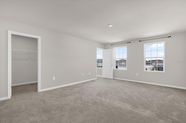 unfurnished bedroom featuring light colored carpet, a spacious closet, and a closet