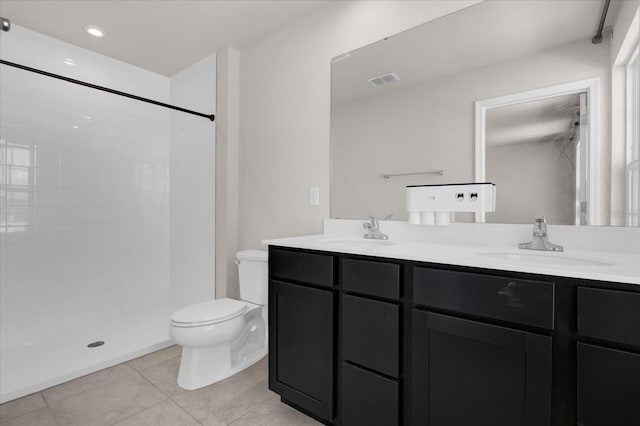 bathroom featuring a tile shower, vanity, toilet, and tile patterned floors