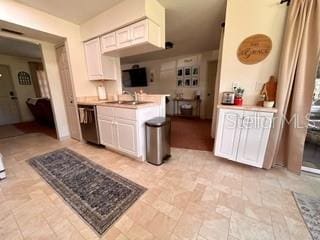 kitchen with dishwasher, white cabinets, and sink