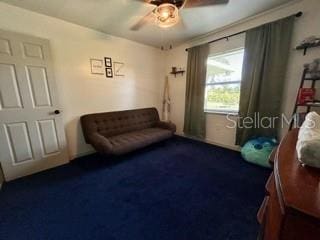 living area with ceiling fan and dark carpet