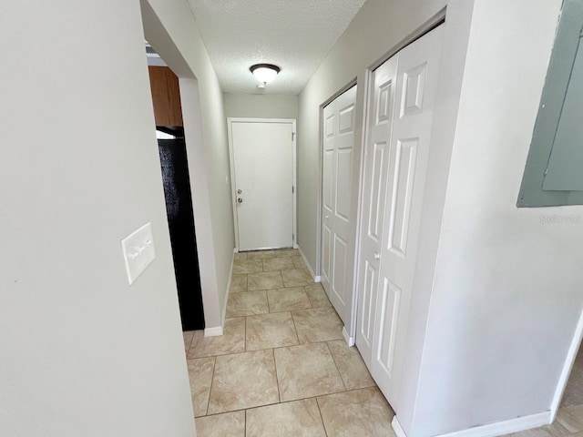 hall with electric panel, light tile patterned flooring, and a textured ceiling