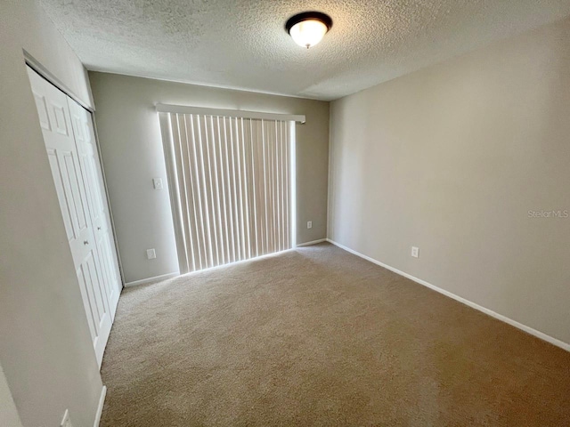 spare room featuring carpet and a textured ceiling