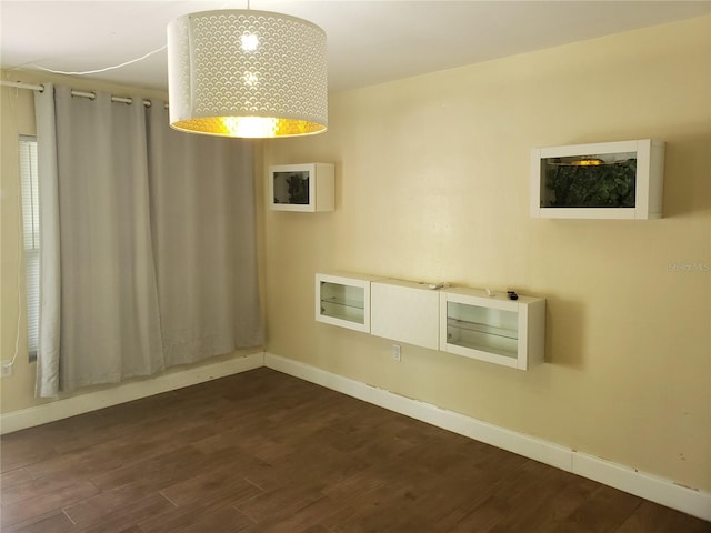 spare room featuring dark wood finished floors and baseboards