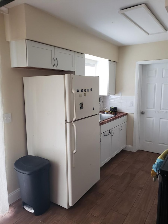 kitchen with freestanding refrigerator, white cabinetry, and a sink