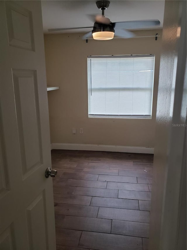 unfurnished room featuring ceiling fan, baseboards, and dark wood-style flooring