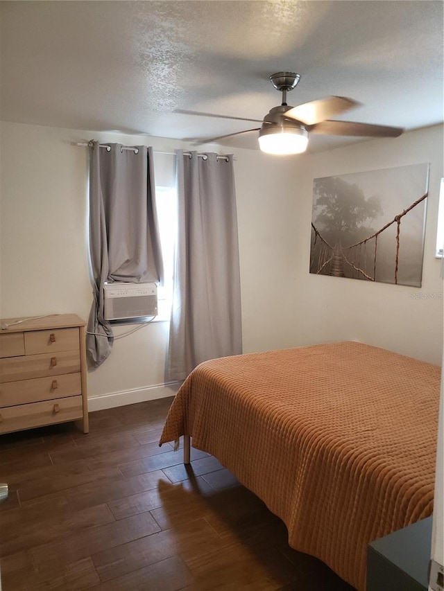 bedroom with baseboards, dark wood-style floors, ceiling fan, a textured ceiling, and cooling unit