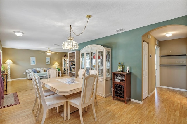 dining space with light hardwood / wood-style floors, a textured ceiling, and ceiling fan with notable chandelier