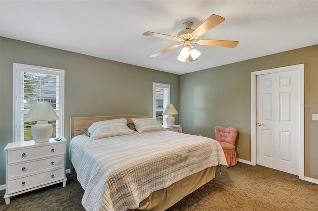 bedroom with dark colored carpet, multiple windows, and ceiling fan