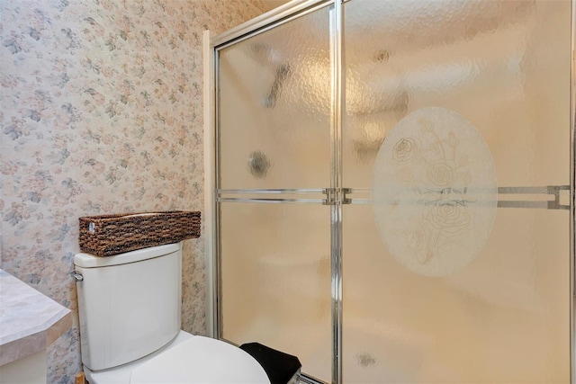 bathroom featuring toilet and a shower with shower door