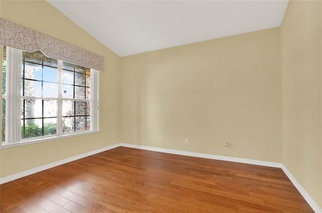 spare room with wood-type flooring and lofted ceiling