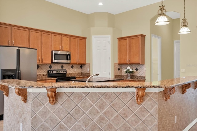 kitchen featuring hanging light fixtures, a kitchen breakfast bar, appliances with stainless steel finishes, and tasteful backsplash