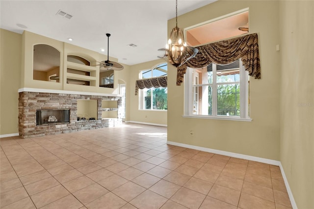 unfurnished living room featuring a stone fireplace, ceiling fan with notable chandelier, and light tile patterned floors