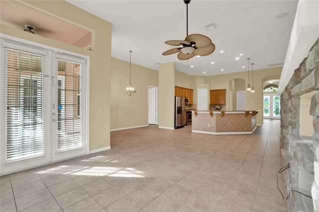 unfurnished living room featuring light tile patterned floors and ceiling fan with notable chandelier