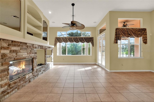 unfurnished living room with a fireplace, ceiling fan, light tile patterned floors, and built in shelves