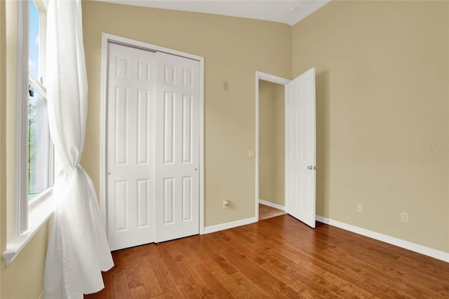 unfurnished bedroom with a closet, lofted ceiling, and wood-type flooring