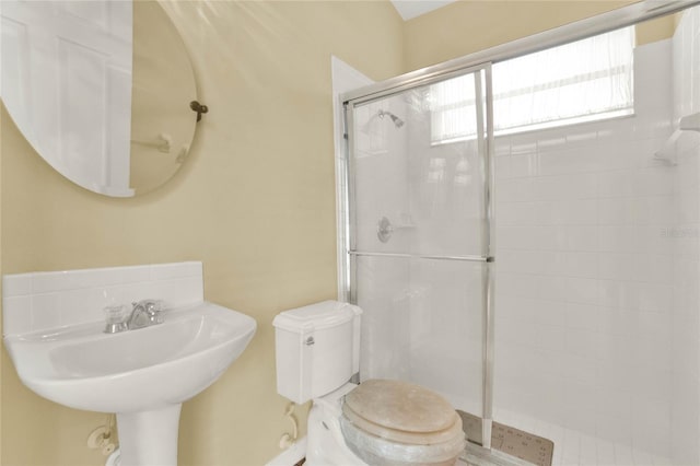 bathroom featuring sink, toilet, and a shower with door