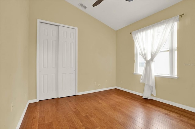 unfurnished bedroom featuring hardwood / wood-style floors, ceiling fan, a closet, and vaulted ceiling