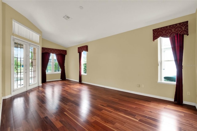 empty room featuring lofted ceiling, a healthy amount of sunlight, and dark hardwood / wood-style floors