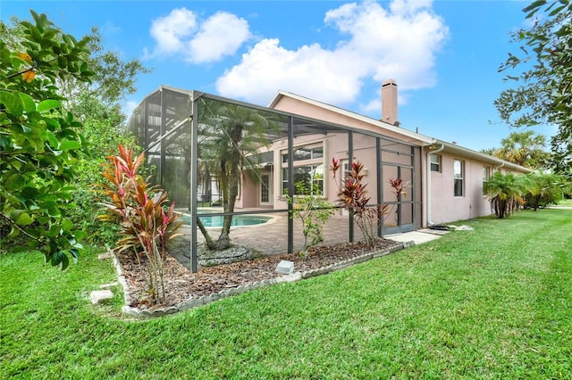 back of house with glass enclosure and a yard