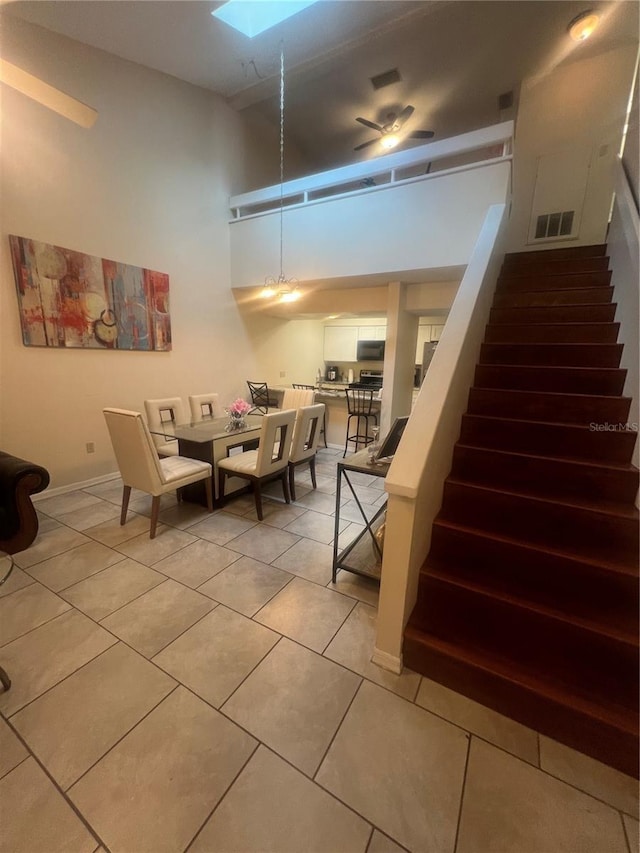 dining space with visible vents, a skylight, stairway, light tile patterned floors, and baseboards
