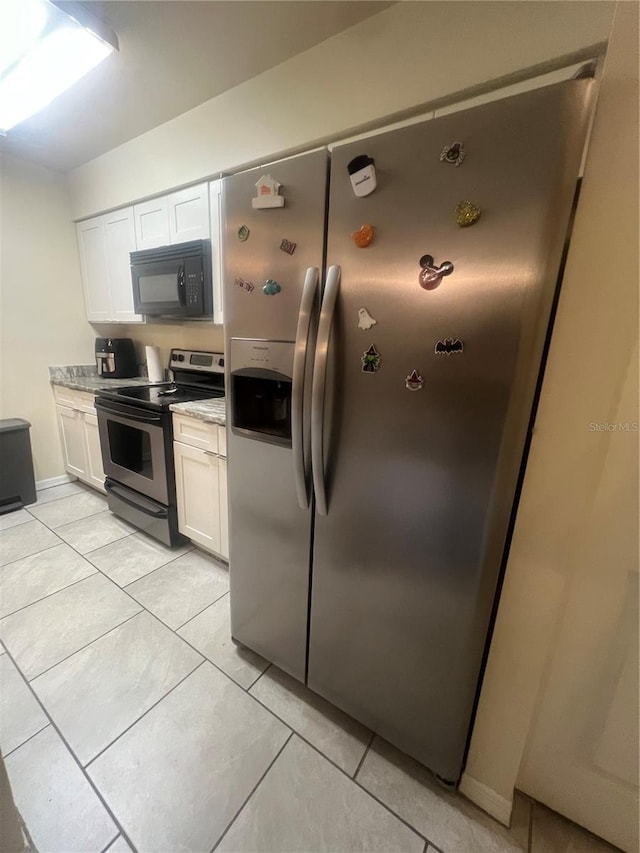 kitchen with light stone countertops, appliances with stainless steel finishes, light tile patterned floors, and white cabinets