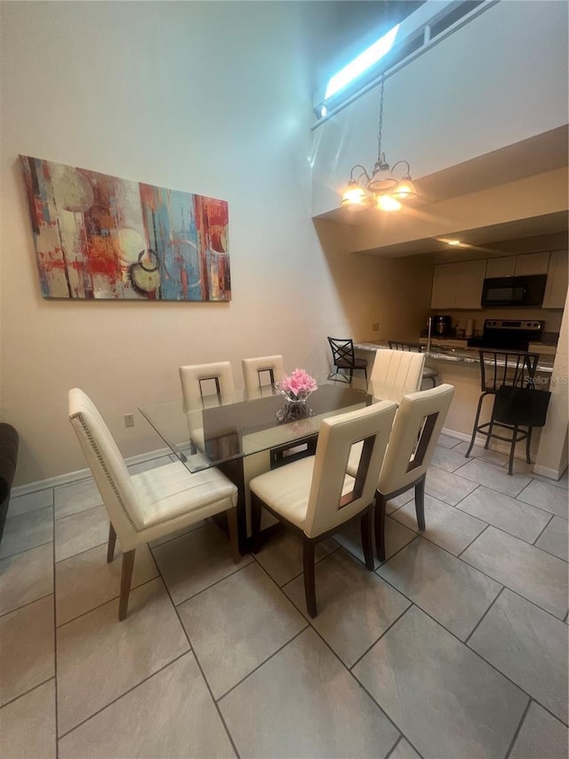 dining area with light tile patterned floors, baseboards, and a high ceiling