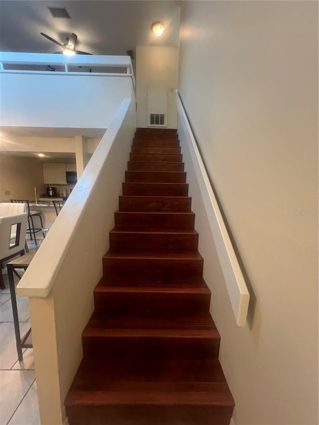 stairs featuring tile patterned floors and ceiling fan