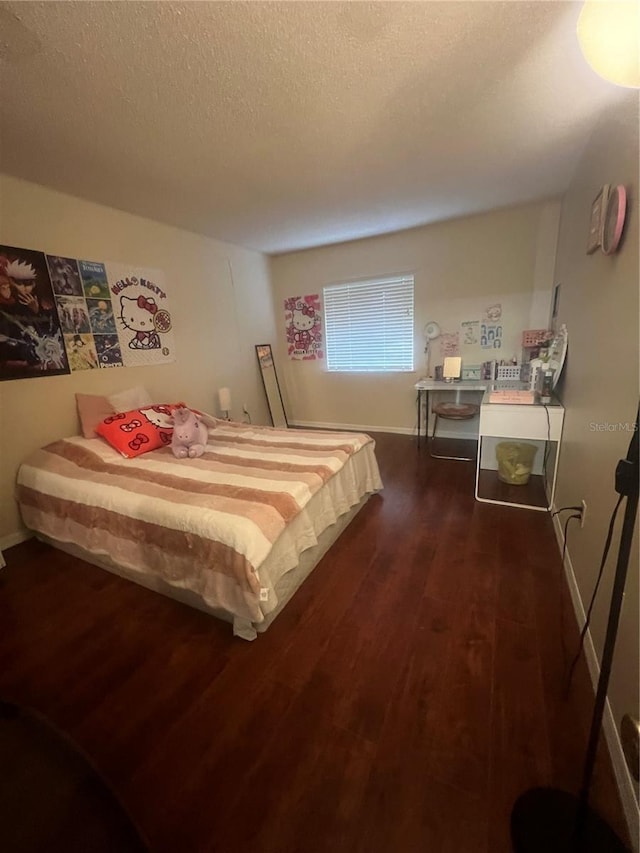 bedroom with baseboards, a textured ceiling, and dark wood-type flooring