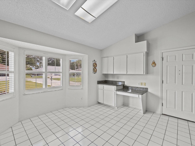 kitchen with a textured ceiling, light tile patterned floors, plenty of natural light, and white cabinets